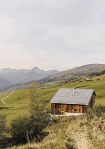 Die neuen Wände, Böden und Einbauten sind in hellem Fichten- und Eichenholz. Ein Ofen ist zentral im Raum positioniert. Fotos: Edon Miseri Photography