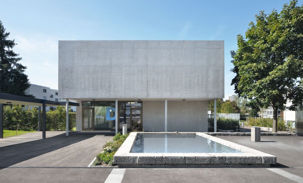 Die Kopfseite zeigt sich als monolithische Fläche in roh belassenem Sichtbeton.