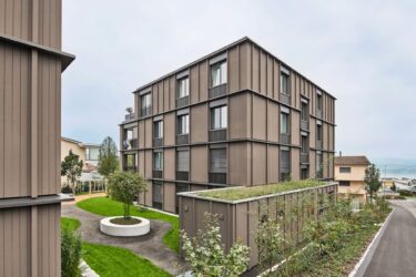 Die Fassadenhaut in Holz hebt sich von den dunkel einbrennlackierten Metallflächen ab.