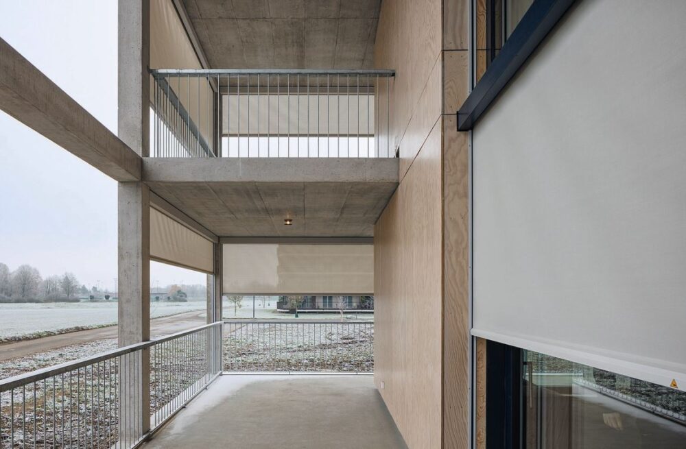 Vor den raumhohen Verglasungen und entlang der umlaufenden Balkone bilden die Senkrechtmarkisen eine textile Schicht vor der Fassade.