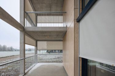 Vor den raumhohen Verglasungen und entlang der umlaufenden Balkone bilden die Senkrechtmarkisen eine textile Schicht vor der Fassade.